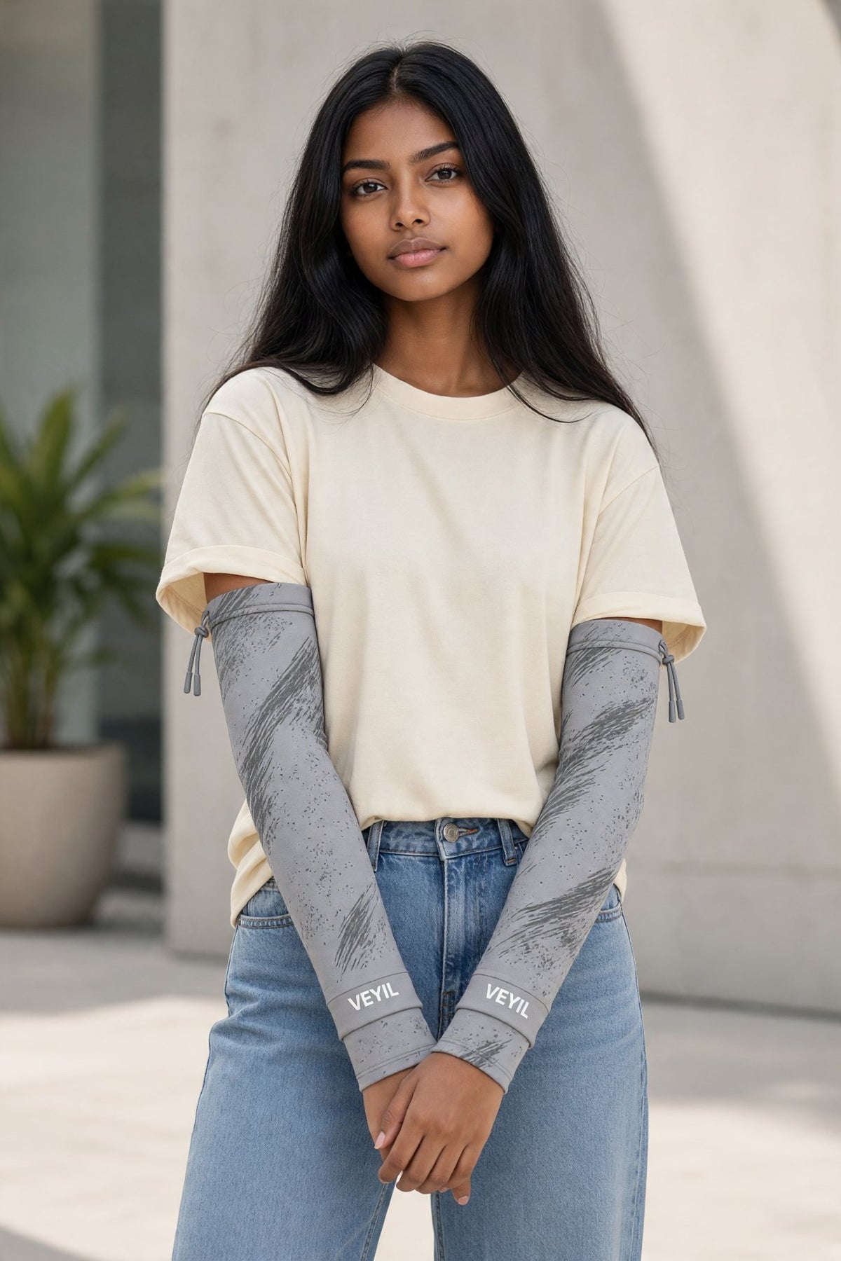 Woman wearing grey VEYIL UPF 50+ cooling arm sleeves with a cream T-shirt and jeans